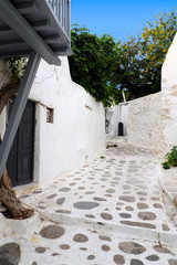 One of the charms of Mykonos, Greek island in the heart of the cyclades, are its narrow streets : white houses with small flowered balconies touching almost above paved streets