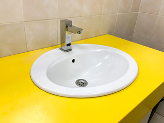 Yellow modern washing basin in a public restroom