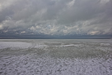 Endless winter frozen lake Plescheevo, horison and dramatic gray clouds on heavy sky