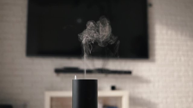Air humidifier in a modern cozy smart house in front of plasma TV. Vapor coming from electric air humidifier in interior. Humidifier Pumps Out Water Vapor