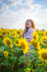 Fototapeta na wymiar Happy girl with blond long hair on a field of sunflowers