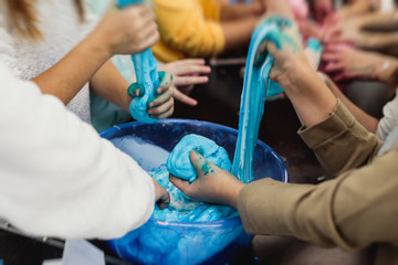 Group of kids making a multicoloured slime, pink, blue and white slime toy on kids birthday party,...