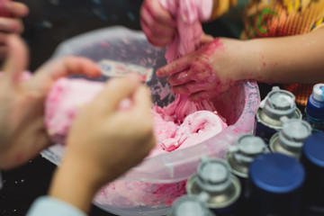 Group of kids making a multicoloured slime, pink, blue and white slime toy on kids birthday party, kid playing with slime, homemade slime