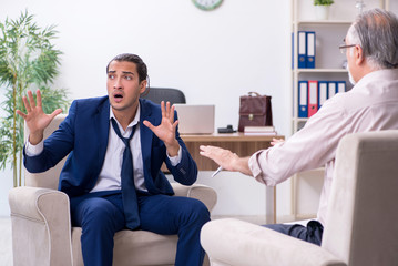 Young man visiting old male doctor psychologist