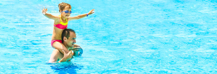 Little girl and happy dad having fun together in outdoors swimming pool