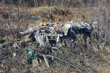 big pile of garbage in gray dry grass on nature