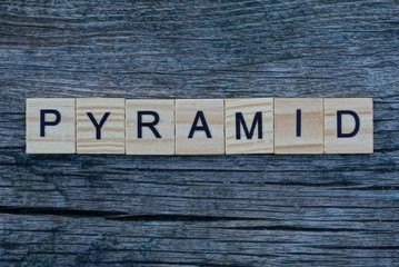 Fototapeta premium word pyramid made from gray wooden letters lies on a gray table