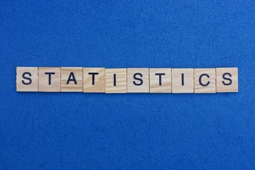 word statistics made from wooden gray  letters lies on a blue background