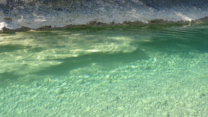 kalkfelsen an einem flusslauf mit glasklarem wasser