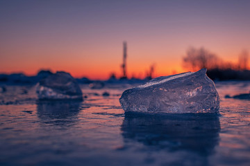 some pieces of clear ice close up on frozen water at sunset