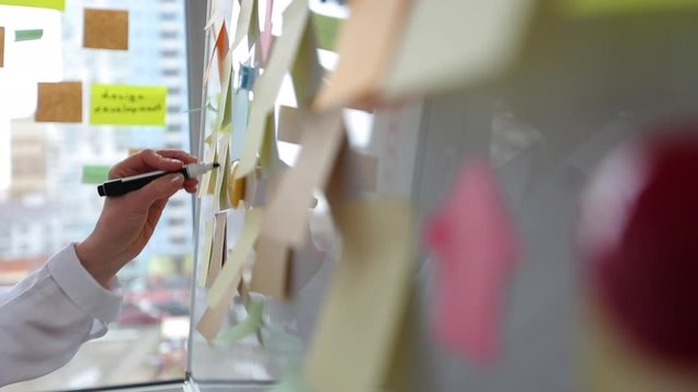 A business woman in the office uses post sticky notes to share an idea. Concept of brainstorming, team.