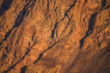 Sunny nature background of rockies in sunlight. Vivid natural mountain texture of big rough rocks. Full frame of bright giant craggy surface. Rocky mountain close-up. Plane of shiny rocks on sunset.