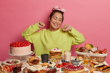 Cheerful sweet tooth girl stretches with pleasure, surrounded by bakery production, comes on...