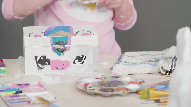 Painting with a white acrylic paint unicorn paper mache figurine.