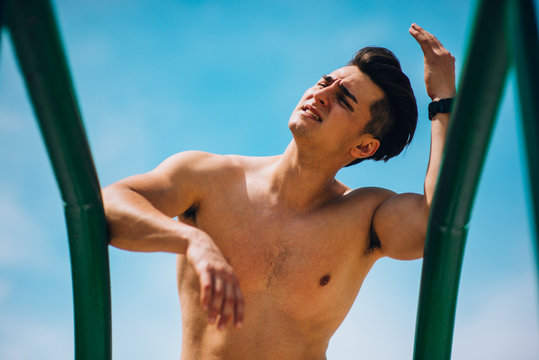 Shirtless sportsman training on parallel bars