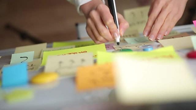Business woman writes notes using post stickers on paper. Brainstorming, teamwork.