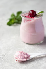 Delicious Italian dessert cherry panna cotta with fresh cherries and mint in jars. Light grey stone...