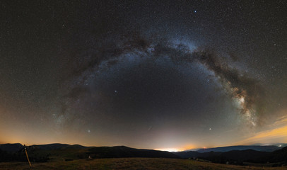 Long exposure panorama of full band of Milky Way above desert mountains an lake