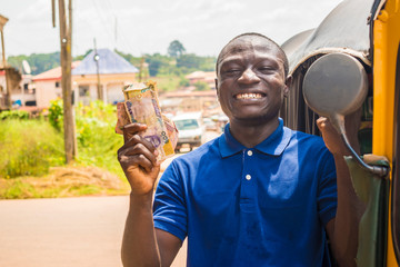 cheerful african man winner holding some money celebrating and jubilant standing next to an auto rickshaw taxi outdoor