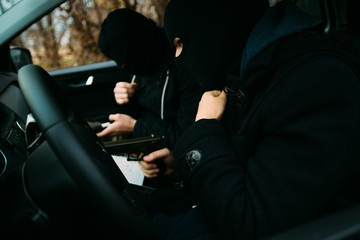 Bank robbers with their masks on pointing at the map prepared for robbing the bank,sitting in the...