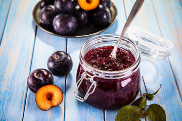 Plums and preserves on wooden background