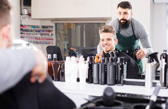 male hairdresser showing resulting haircut to client at hair salon