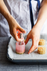 A young woman making mooncakes by using a mooncake press set on a baking tray