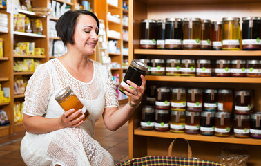 Woman choosing honey in store