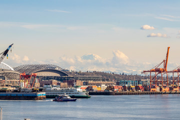 Obraz premium Clouds forming and moving in front of Mt. Rainier and part of the harbor island with containers in the Elliott Bay in Seattle, Washington on a beautiful day.