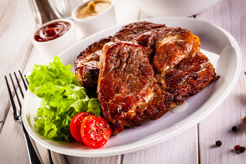 Grilled steak and vegetables on wooden background