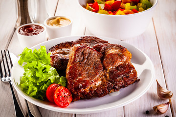 Grilled steak and vegetables on wooden background