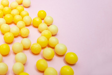 Yellow colorful round dragees of vitamin c, ascorbic acid on pink background, copy space