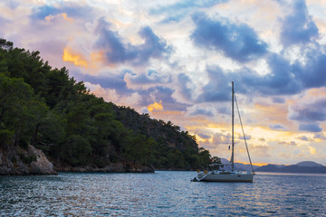 Sailing yacht anchored in the bay against the background of a bright sky covered with multicolored...