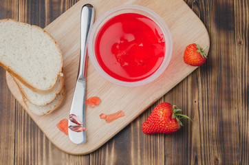Strawberry jam. Bread and strawberry jam on a wooden table with jar of jam and fresh strawberry. Top view. Making sandwiches with strawberry jam.