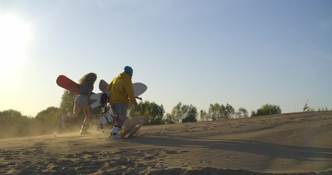 a group of people on the top dunes funny run on sandboarding gear