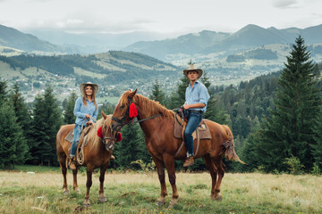 cowboy couple on horsebacks in mountains.