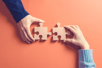 Two hands holding jigsaw, Concept for teamwork Building a success. - obrazy, fototapety, plakaty