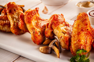 Barbecued chicken wings with french fries and vegetable salad on timber