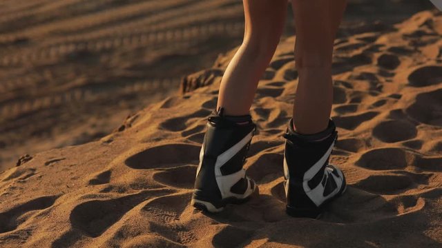 beautiful feet in sandboarding and snowboarding gear on the sand in the dunes