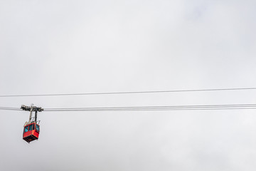 Photo of a cable way in the mountains. Red cableway cabine in the air diving into the clouds. Cableway to the top of Lomnicky stit, High Tatras, Slovakia.
