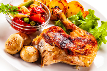 Barbecued chicken leg with chips and vegetables on white background