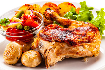 Barbecued chicken leg with chips and vegetables on white background