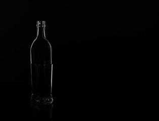 Silhouette of a glass bottle on a black background . Empty space for your lettering.