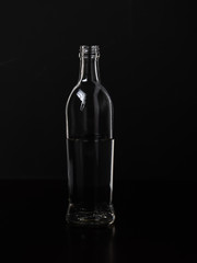 Silhouette of a glass bottle on a black background . Empty space for your lettering.