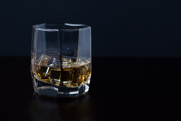 Glass of Scotch whiskey with ice on a black background. empty space for your text.