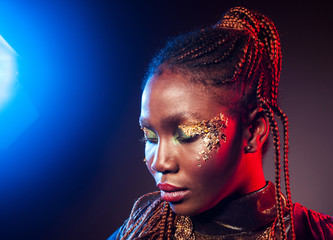 Naklejka na ściany i meble Young African woman with afro hairstyle and golden shiny makeup. Studio shot. Classic Blue 2020 trend color