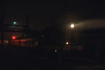 Fototapeta na wymiar passenger train in mystical night illumination follows in a little fog