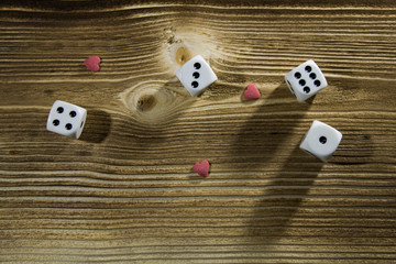 white dice and small hearts on a wood background