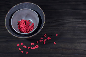 plate with nuts on a black background with scattered hearts