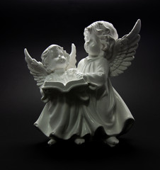 Guardian angel on a dark background two angels are reading a book